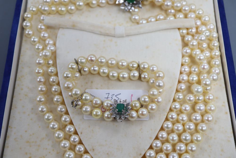 A triple strand cultured pearl necklace and matching bracelet with white metal, emerald and diamond set clasps & 1 other bracelet.